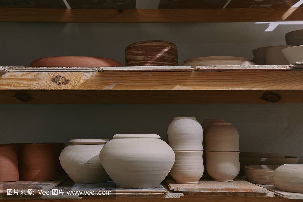 陶艺工作室木制架子上的陶瓷碗和盘子